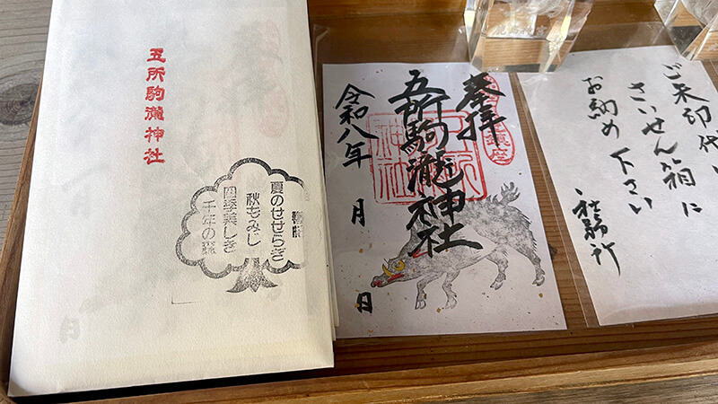 五所駒瀧神社の御朱印見本と授与品案内が並ぶ社務所前