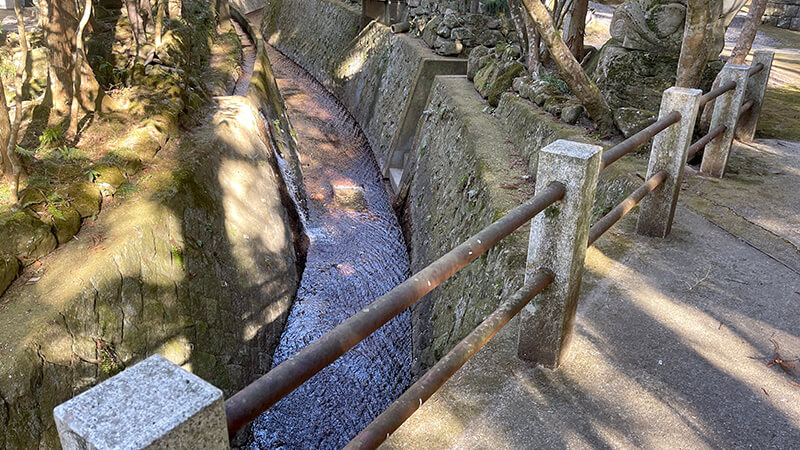 五所駒瀧神社境内の石垣沿いを流れる細い水路と手すり