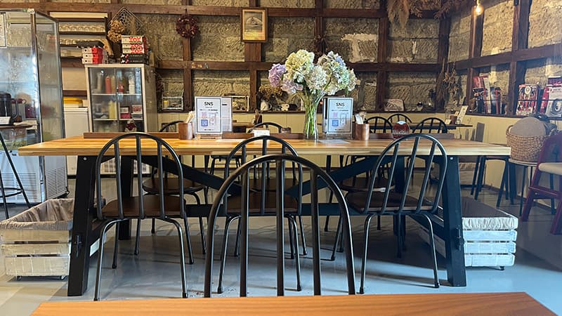 石壁と木の柱に囲まれた蔵cafe 氷菓ふわりの店内テーブル席