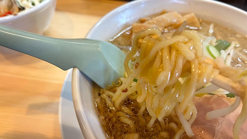 あおり醤油ラーメンのスープを絡めて持ち上げた中細ちぢれ麺