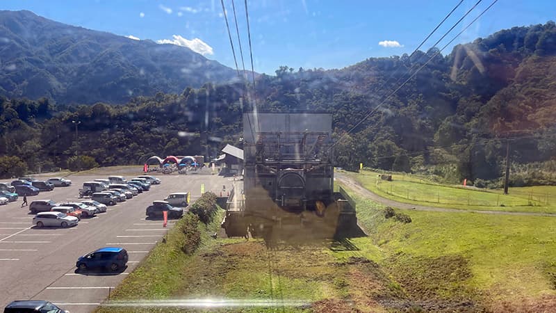 八海山ロープウェーの車内から見下ろした山麓駅と駐車場の車列