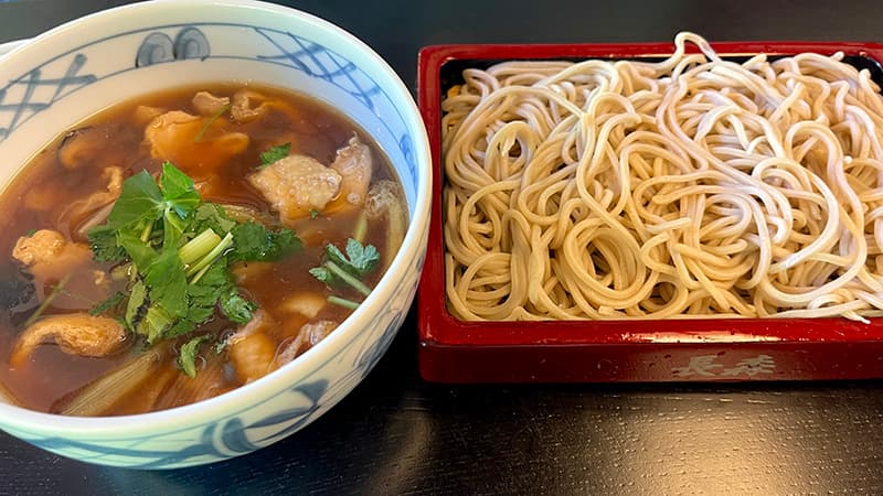 鶏肉とねぎが入った温かいつけ汁と冷たいそばのとりせいろそば